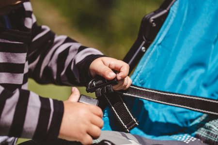 A high angle shot of a child fixing his blue car seat captured on a sunny dayの写真素材
