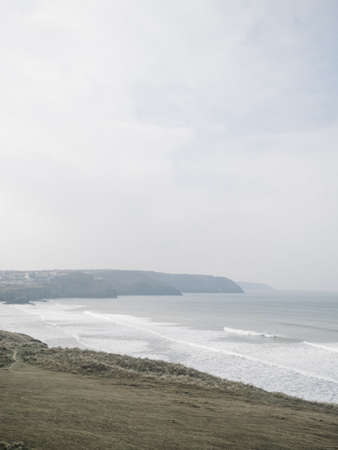 A beautiful scenery of sea waves crashing under a dark cloudy skyの写真素材