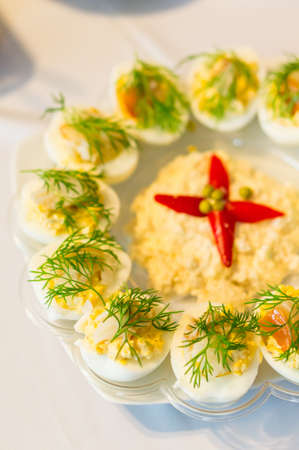 A vertical shot of half-cut cooked eggs with filling on a plateの写真素材