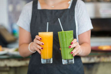 A closeup shot of waitress serving freshly made avocado and mango juices at cafe restaurant