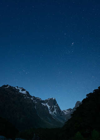 A vertical shot of mountains under a dark blue sky filled with starsの写真素材
