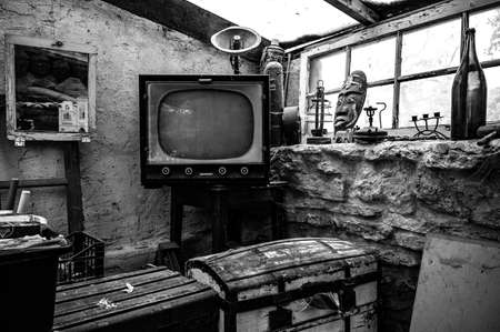 A grayscale shot of a vintage television box in an old house surrounded by retro decorationsのeditorial素材