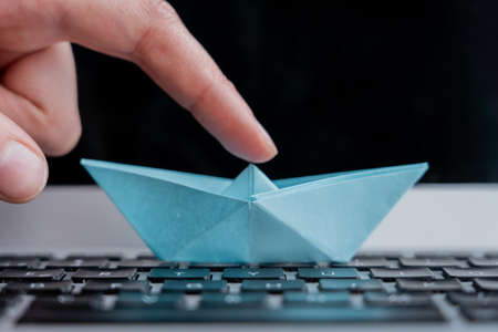 A selective focus shot of a paper boat on the keyboard of a laptopの写真素材