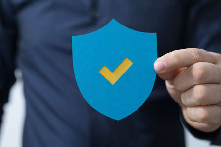 A man holding a protection shield with a checkmarkの写真素材