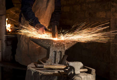 A closeup shot of the hands of a blacksmith hammering a hot horseshoe