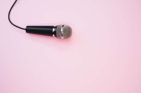 A closeup shot of a microphone with a wire isolated on a pink background with a shadowの写真素材