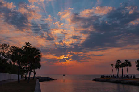 Orange sunset with beaming rays thru the blue and white clouds shining into the inletの写真素材