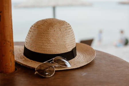 A closeup shot of a sunglasses and a straw hat on a wooden surfaceの写真素材