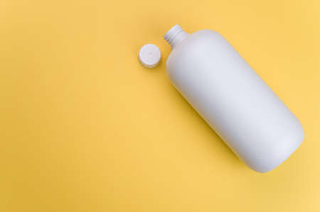A closeup shot of a white plastic container with an open lid on a yellow surfaceの写真素材