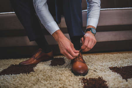 A closeup shot of a groom tying his shoes on the wedding dayの写真素材