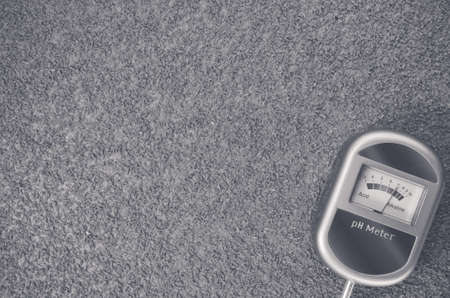 A top view closeup of an analog tool to measure the ph of the soil on a toned rough stone surfaceの写真素材