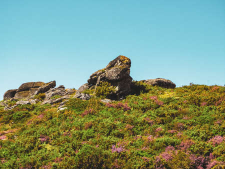 The hills in greens and big rocks under the cloudy skyの写真素材