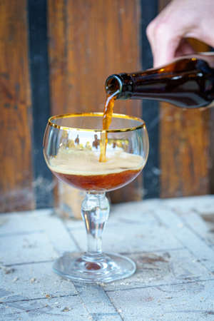 A vertical shot of a person pouring Trappist beer in a glass
