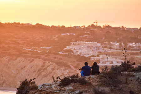A couple admiring the sunset over the beachの写真素材