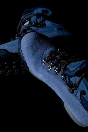 A vertical shot of blue winter trekking boots on black backgroundの写真素材