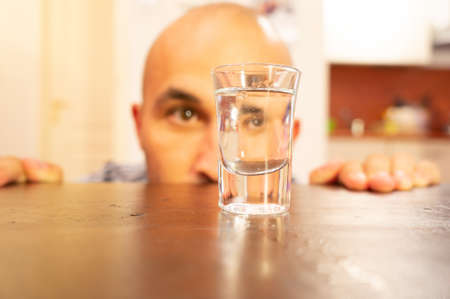 A male staring at a glass filled with alcohol - alcohol addiction conceptの写真素材