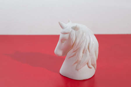 A closeup shot of a white horse head figurine on a red surfaceの写真素材