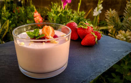 A closeup shot of strawberry yogurt with strawberries  on the black tableの写真素材
