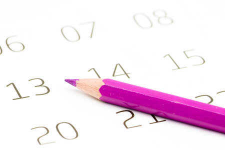 A closeup of a sharp purple pencil on a calendar with a blurry backgroundの写真素材
