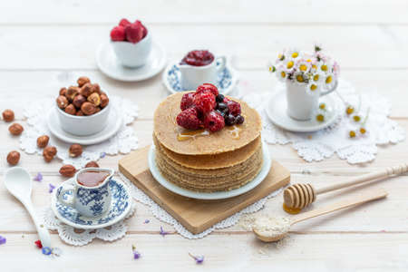 A high angle closeup shot of raw vegan pancakes with honey and berries