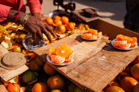 A closeup shot of cut oranges on plates at a market in New Delhi, India