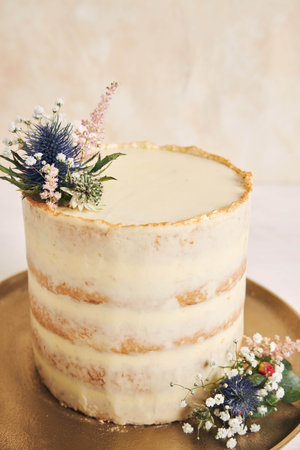 A vertical shot of a beautiful and delicious cake with flower and golden edges on a white background