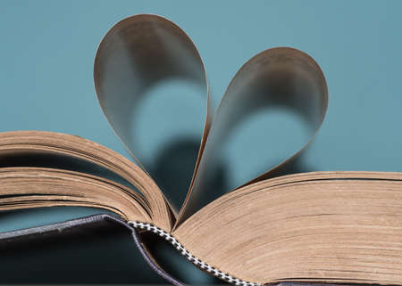 A closeup shot of book pages in heart-shaped with a blue background
