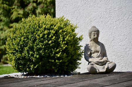 A little statue of Buddha outside the house on a sunny dayの写真素材