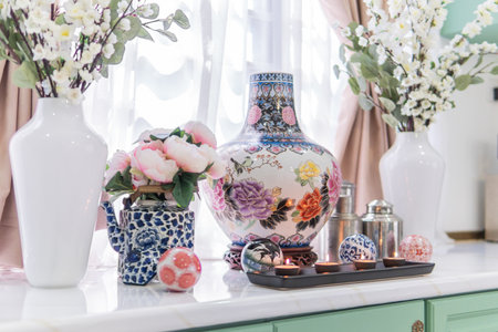 A closeup of the traditional Chinese colorful ceramic vases with flowers in the kitchen with candlesの写真素材