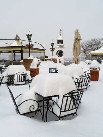 A vertical shot of chairs and tables covered in snow in Novi Sad, Serbiaの写真素材