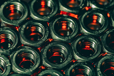 An overhead shot of screw nuts with the red light coming under it
