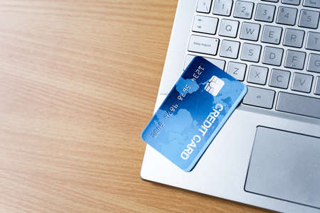 A top view of a credit card on a laptop in background of a wooden surface for a copy spaceの写真素材