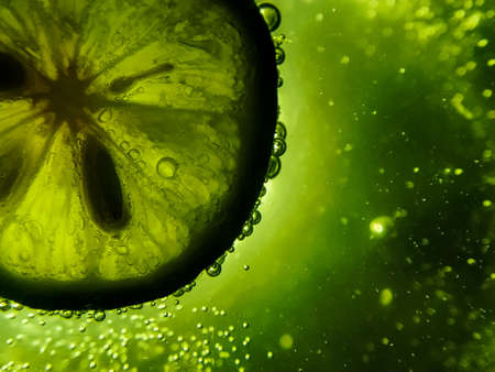 A closeup shot of a slice of lime in a green soda drinkの写真素材