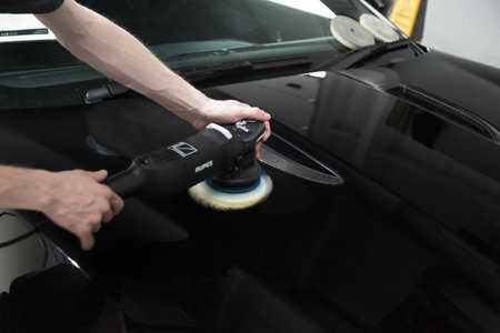 LONDON, UNITED KINGDOM - Sep 12, 2017: Detailer working with a Rupes rotary machine on a black car panelのeditorial素材