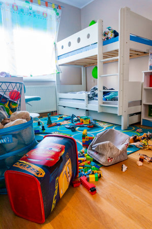 POZNAN, POLAND - Sep 13, 2020: Messy child room with toys laying on the floor next to a bed.のeditorial素材