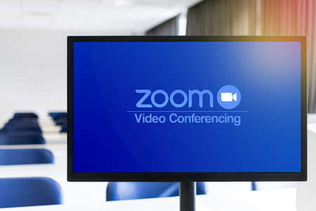 BEER SHEVA, ISRAEL - Dec 20, 2020: Close-up of computer monitor, with zoom brand logo on the screen, empty classroom with out-of-focus background. Distance education concept.のeditorial素材