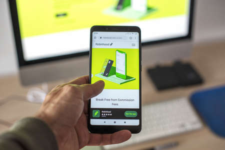 MADRID, SPAIN - Jan 31, 2021: A man checking in his smartphone the website of Robinhood that is an...