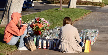 FRESNO, UNITED STATES - Dec 30, 2020: A photo of two grieving teenagers sitting next to candles and...