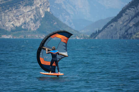 MALCESINE, ITALY - Jul 08, 2020: A Wing-foil surfer practising a very new sport Wing-foil after COVID-19 restrictions on the Garda Lake near Malcesine town in Italy on JUly in 2020.のeditorial素材