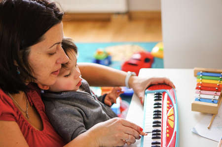 POZNAN, POLAND - Dec 27, 2015: Woman playing with child on a toy piano on tableのeditorial素材