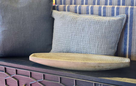 FRESNO, UNITED STATES - Jun 16, 2020: Several textured casual pillows with a long hand made wooden boat shaped platter on a decorative dresser for home decor design ideasのeditorial素材