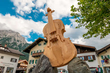 MITTENWALD, GERMANY - Aug 15, 2020: A huge wooden violin with sides, body and fingerboard, built diagonally on two rocks and located in the middle of Mittenwald in Bavariaのeditorial素材