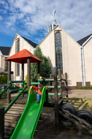 POZNAN, POLAND - Sep 01, 2020: Slide equipment with small boy close by a church in the Stare Zegrze areaのeditorial素材