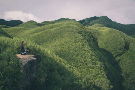KOHIMA, INDIA - Jul 29, 2019: A Canadian Young Women Meditating in the Unexplored Dzukou valley of Nagaland in one of the Northeast states of Indiaのeditorial素材