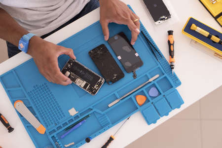 CUPERTINO, UNITED STATES - Aug 05, 2020: A man opening an iPhone to fix its parts like a broken screen, dead battery or phone flats.のeditorial素材