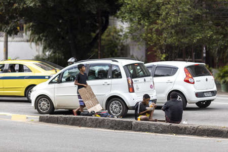 RIO DE JANEIRO, BRAZIL - May 27, 2020: Rio de Janeiro, Brazil - May 27, 2020: Children begging and eating on the side of a freeway with cars at a traffic light during COVID-19 outbreakのeditorial素材