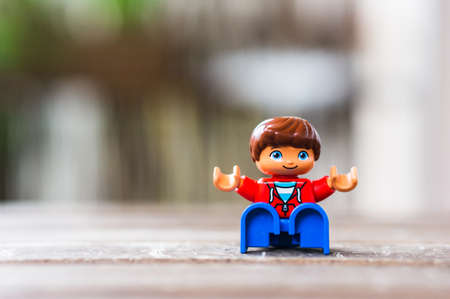 POZNAN, POLAND - Jul 13, 2020: Lego Duplo boy figurine sitting on a wooden surface in soft focus backgroundのeditorial素材