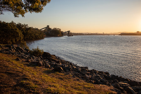 A panoramic shot of a stony shoreline with the sun in the horizon