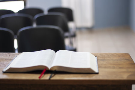 A closeup shot of an open holy bible on a wooden table with a blurred backgroundの写真素材