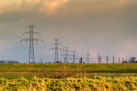 A beautiful shot of transmission lines in the field with a cloudy sky in the background